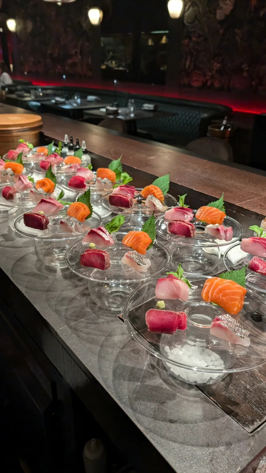 Sashimi plated on ice in glass dishes before service.